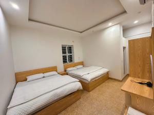 a bedroom with two beds and a wooden desk at Tay Bac Hotel in Mộc Châu