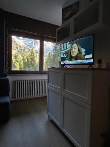 a television sitting on a dresser in a room with a window at Hope Home Trentino in San Martino di Castrozza