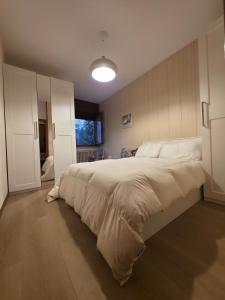 a bedroom with a large bed with white sheets at Hope Home Trentino in San Martino di Castrozza