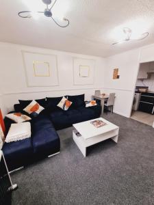 a living room with a blue couch and a table at Elisha's City Apartment in Hackbridge