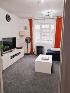 a living room with a couch and a tv at Elisha's City Apartment in Hackbridge