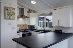 a kitchen with white cabinets and a black counter top at Tranquil Lodge with river views in Hambleton