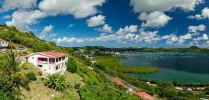a house on a hill next to a lake at Studio Zen Attitude à 10 minutes des belles plages in Le Marin