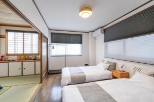 a bedroom with two beds and a window at Guest Houseふくふく in Shimonoseki