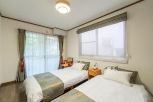 two beds in a room with a window at Guest Houseふくふく in Shimonoseki