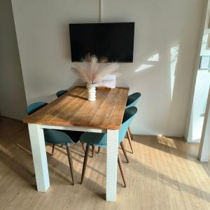 a dining room table with blue chairs and a tv at Studio In het Dorp in Middelstum