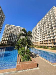 two large buildings with a palm tree in front of a swimming pool at Saekyung Lapu-lapu in Suba