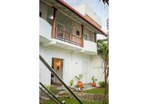 a white house with a balcony on top of it at South Roots in Unawatuna
