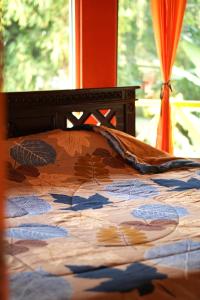 a bed with a comforter with leaves on it at Swindo Homestay 77, Room 1 in Berastagi