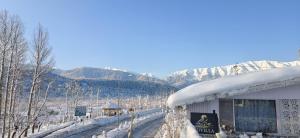 a building covered in snow with mountains in the background at Id villa in Tangmarg