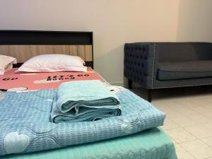 a bed with a blanket and a chair in a room at Impact Arena C5 by Jintana in Thung Si Kan