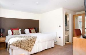 a bedroom with a large white bed with red pillows at Redesdale Arms Hotel in Moreton in Marsh