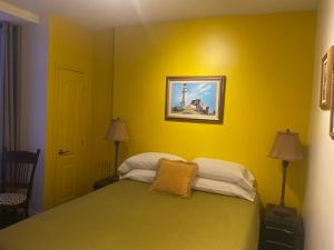 a bedroom with a bed with a yellow wall at Le Saint Louis de lotbinière in Lotbinière