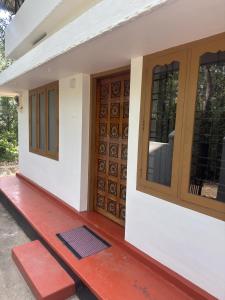 a house with wooden doors and a red porch at Hibisco Hideout in Meenangadi +3 photos