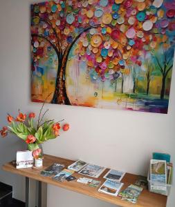 a painting of a tree on a wall next to a table at Au Coin du Bois in Theux