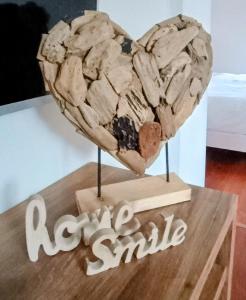a heart sculpture on a wooden table with the words happy smile at Au Coin du Bois in Theux +4 photos