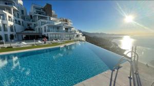 a swimming pool with a view of the ocean and buildings at Seafront 2B Apartment with Pool, Spa & Gym Torrox in Torrox