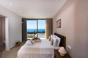a bedroom with a large bed with a large window at Dreamcatcher Villas by PaxosRetreats in Velianitátika +68 photos