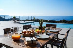 a wooden table with a bowl of fruit and a bowl of orange juice at Dreamcatcher Villas by PaxosRetreats in Velianitátika