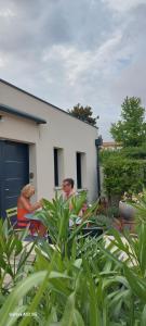 two men and a woman sitting in front of a house at AU GRAIN D'ORGE in Échiré