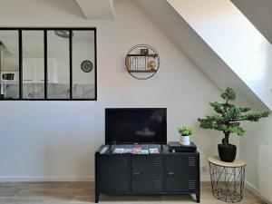 a living room with a tv on a black cabinet at Chez Vincent - Centre Historique de Colmar avec parking inclus in Colmar