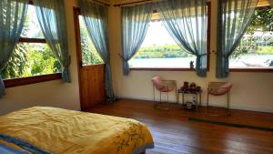 a bedroom with a bed and two chairs in front of windows at Nhà Bên Hồ in Bảo Lộc +23 photos