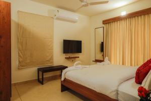 a bedroom with a bed and a flat screen tv at River Whisper Villa in Cochin