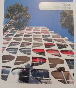 a tall white building with windows and a palm tree at CHEZ FLO ET NANO in La Grande Motte