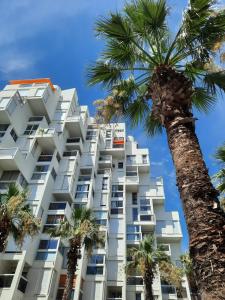 a white building with palm trees in front of it at CHEZ FLO ET NANO in La Grande Motte