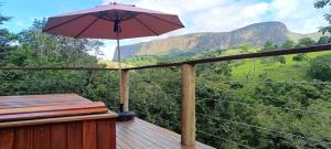 a balcony with an umbrella and a view of a mountain at Chalé Vertente da Canastra in São Roque de Minas