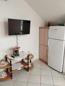 a kitchen with a white refrigerator and a tv on the wall at lopar 239 in Lopar