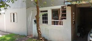 a tree in front of a house with a window at casa aconchegante para descansar in Alegrete