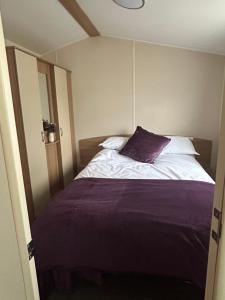 a bedroom with a bed with a purple pillow at Rowan 42 in New Milton +10 photos