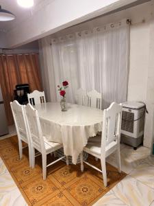 a white table with white chairs and a vase with flowers at Manzanares Homestay in San Jose