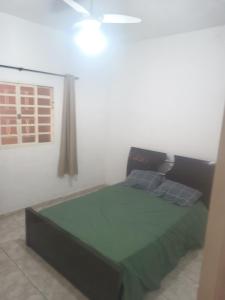 a bedroom with a green bed with a window at Casa familiar in Vespasiano