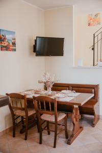 a dining room table with chairs and a tv on the wall at La Casetta - un piccolo angolo di pace in Piccianello