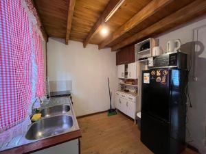 a kitchen with a sink and a black refrigerator at Cabaña Amancay Fuy in Puerto Fuy