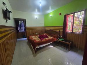 a bedroom with a bed in a room with green walls at Padayappa Residency in Kodaikānāl