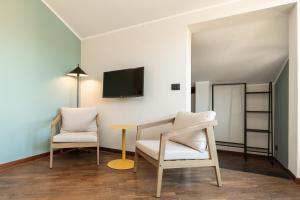 a room with two chairs and a table and a tv at Genova Suite Art in Genoa