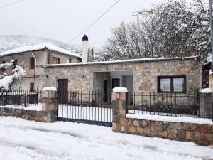 a stone house with a fence in the snow at Stymfalia Cozy Village Guesthouse in Kartérion