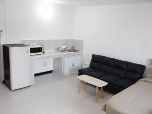 a living room with a black couch and a kitchen at Hi Impact Muangthong T9 in Nonthaburi