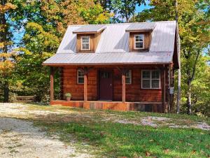 a log cabin with a metal roof and a porch at The Hampton - An Amish Built Deluxe Log Cabin in Genoa