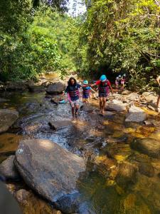 a group of people crossing a stream in the forest at Riverview Adventure Resort in Kitulgala