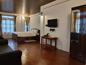 a bedroom with a bed and a tv and a couch at Coralberry Inn in Jāmb +14 photos