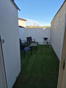 a patio with two chairs and a table and grass at Maison mitoyenne in Gignac-la-Nerthe +6 photos