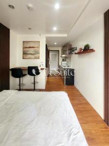 a bedroom with a large white bed and a kitchen at Oak Suite in Baguio