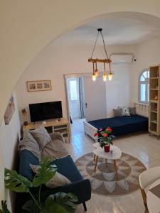 a living room with a blue couch and a tv at Κυκλαδίτικο σπίτι με θέα Villa Mimika in Perissa
