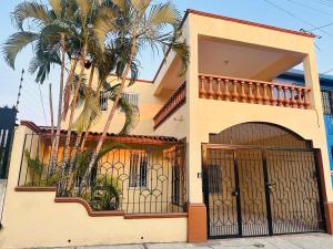 a house with a gate and a palm tree at Colimota in Colima