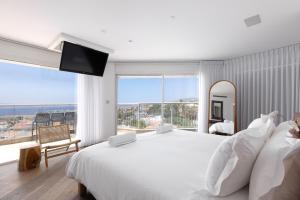 a white bedroom with a large bed and a large window at Kedem Eilat קדם אילת in Eilat