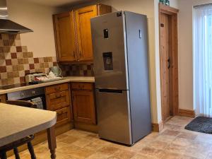 a stainless steel refrigerator in a kitchen with wooden cabinets at Coastline cottage Pakefield, 2 minutes walk to the beach in Pakefield